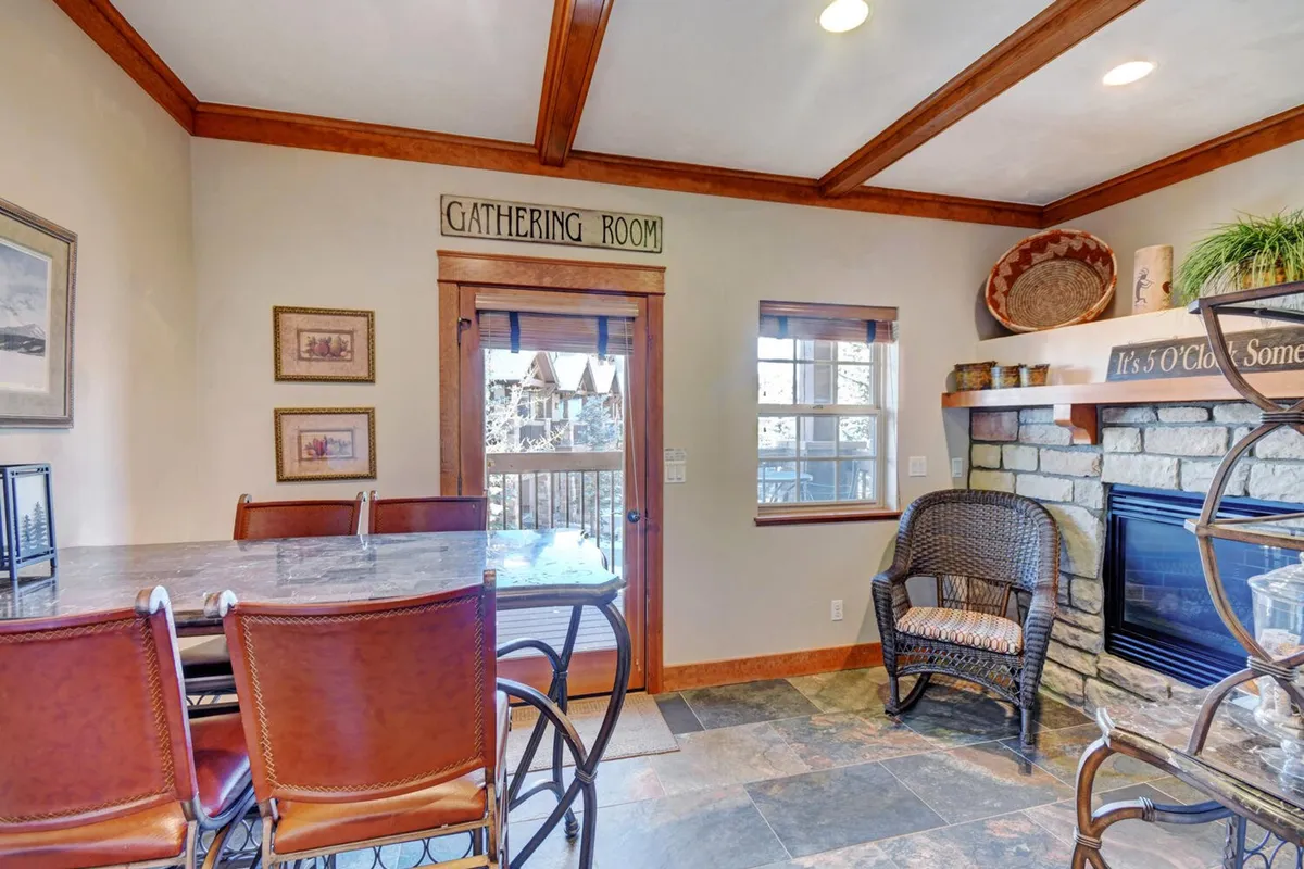 The gathering room showcases a stone fireplace, bar stools, and a woven basket, conveying a cozy, communal atmosphere perfect for family gatherings, board games, or relaxing evenings after outdoor excursions.