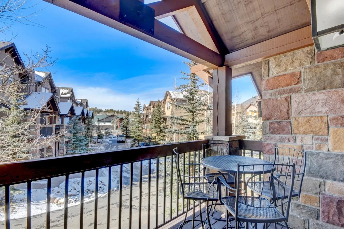 This exterior image features a balcony seating area with views of neighboring buildings and surrounding trees. The atmosphere is relaxed, suggesting a space where guests might gather before or after venturing to local attractions like the Grand Park Rec Center.